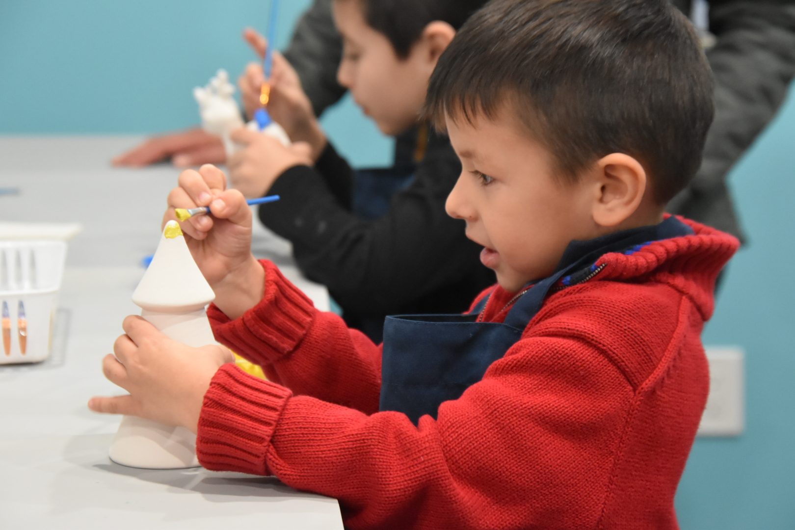 Boy intently painting a ceramic gnome at the Open Craft table.