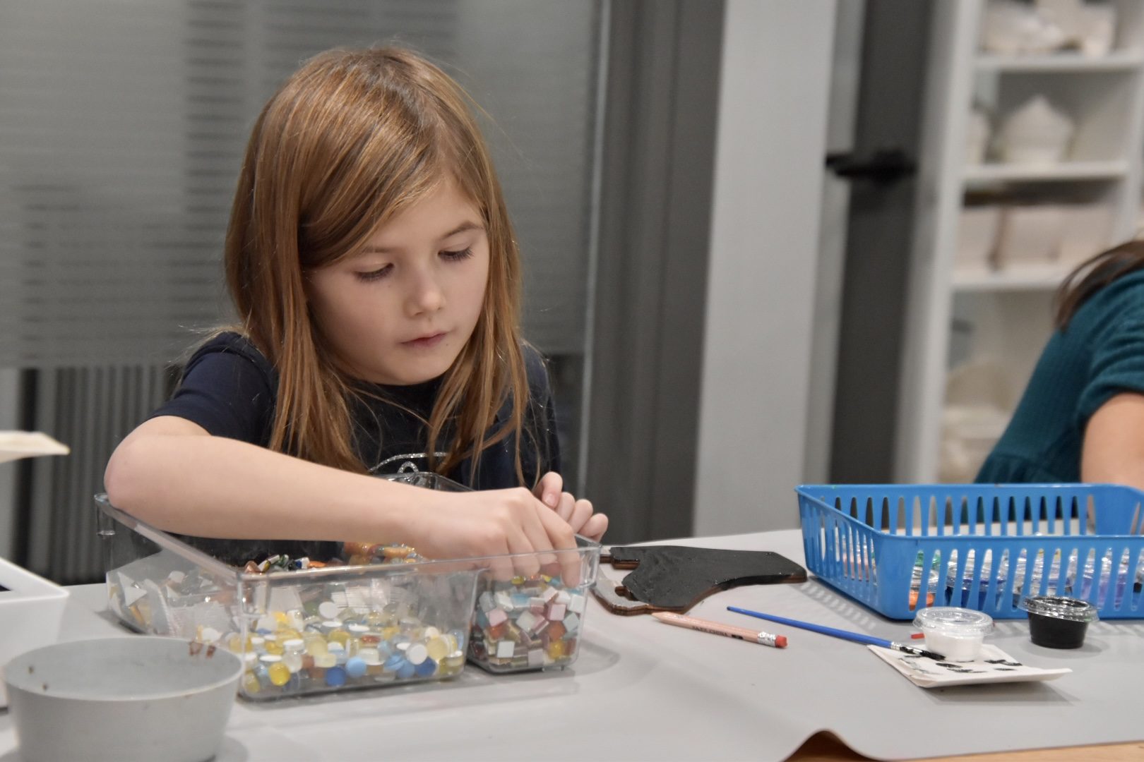 A child working on a mosaic project at the Open Craft table.